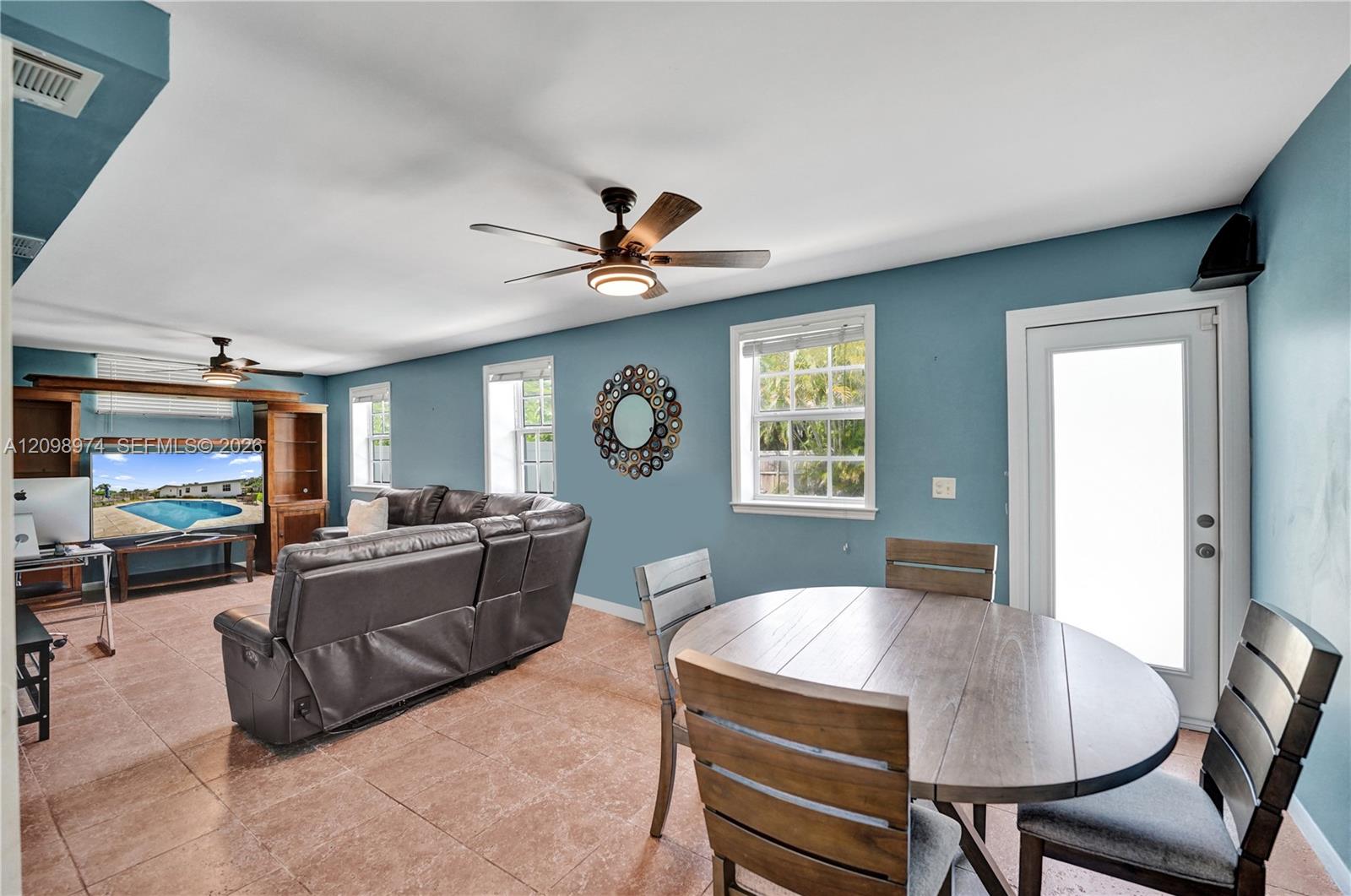 Living and dining room with blue walls, a gray sectional, and an oval wood dining table.