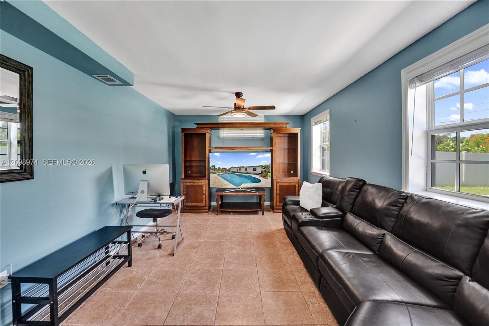 Living room with a dark leather sectional, blue walls, and a wooden entertainment center.