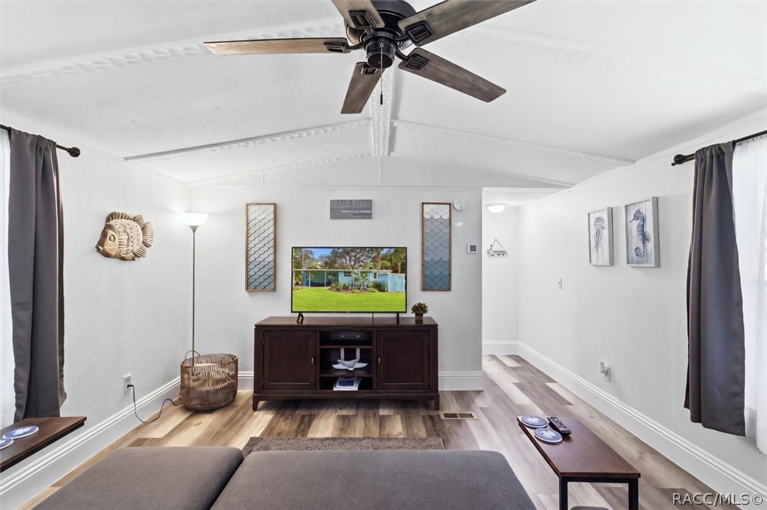 Living room with vaulted ceiling, ceiling fan, sectional sofa, and media console.