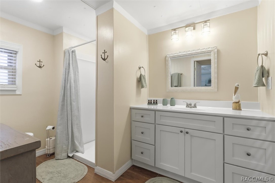 Bathroom with a long white vanity and framed mirror beside a curtained shower.