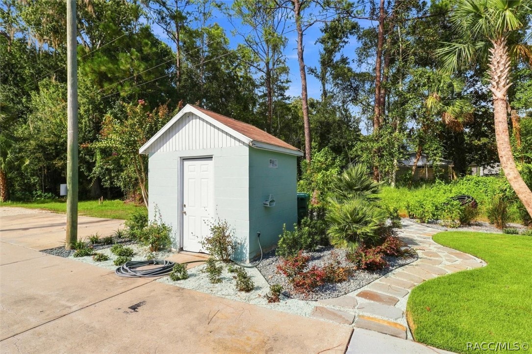 Small detached shed beside a landscaped driveway and curving stone walkway.