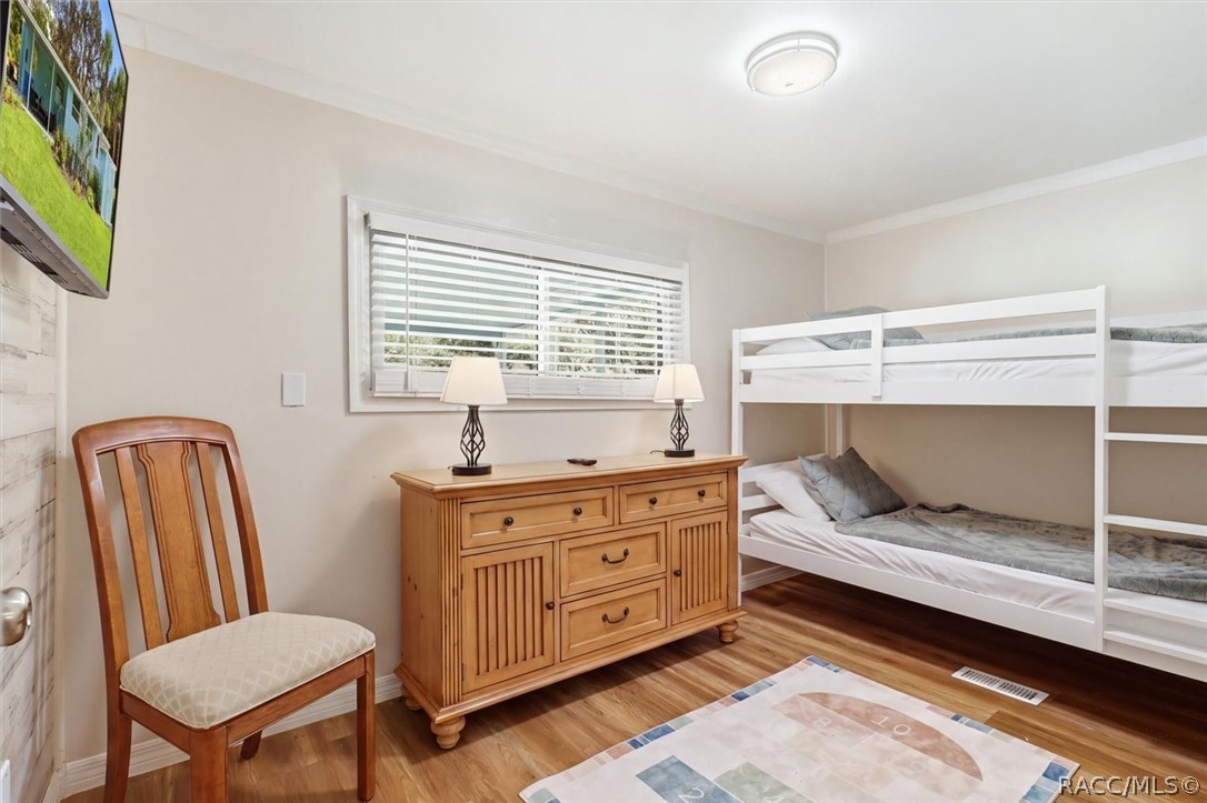 Bedroom with a white bunk bed, wooden dresser, and window with blinds.