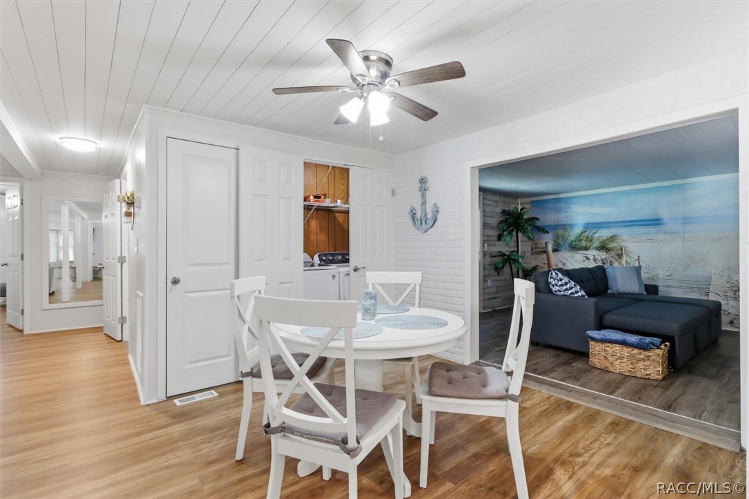 Dining area with a round white table, adjoining a living room with a beach mural.