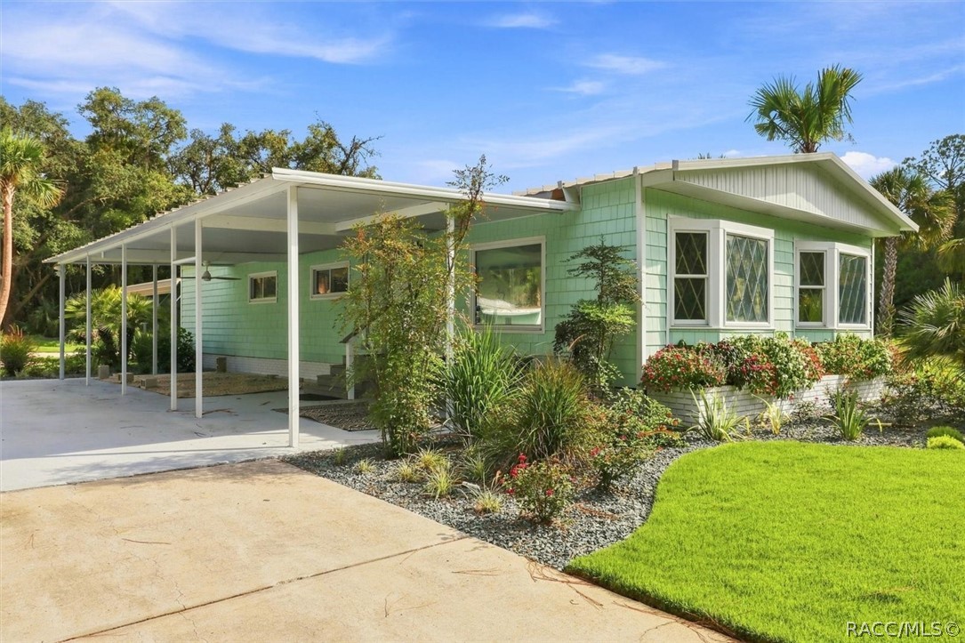 Mint-green single-story home with a covered carport and landscaped front yard.
