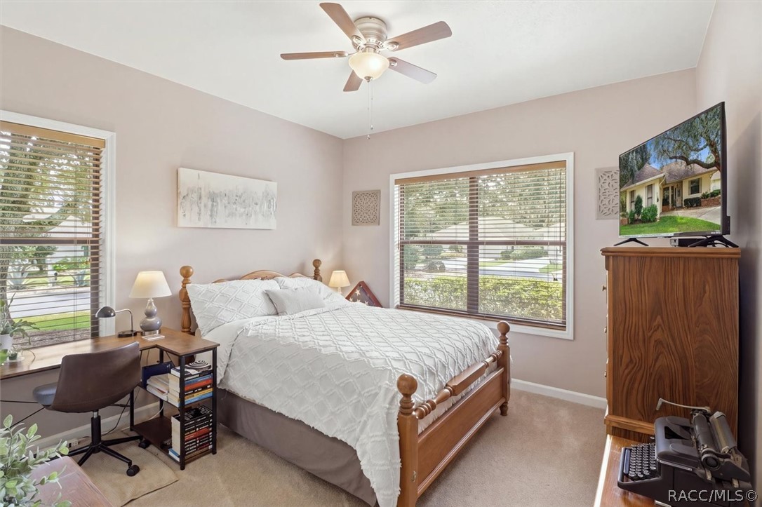 Bedroom with a wood bed, desk by the window, and ceiling fan.