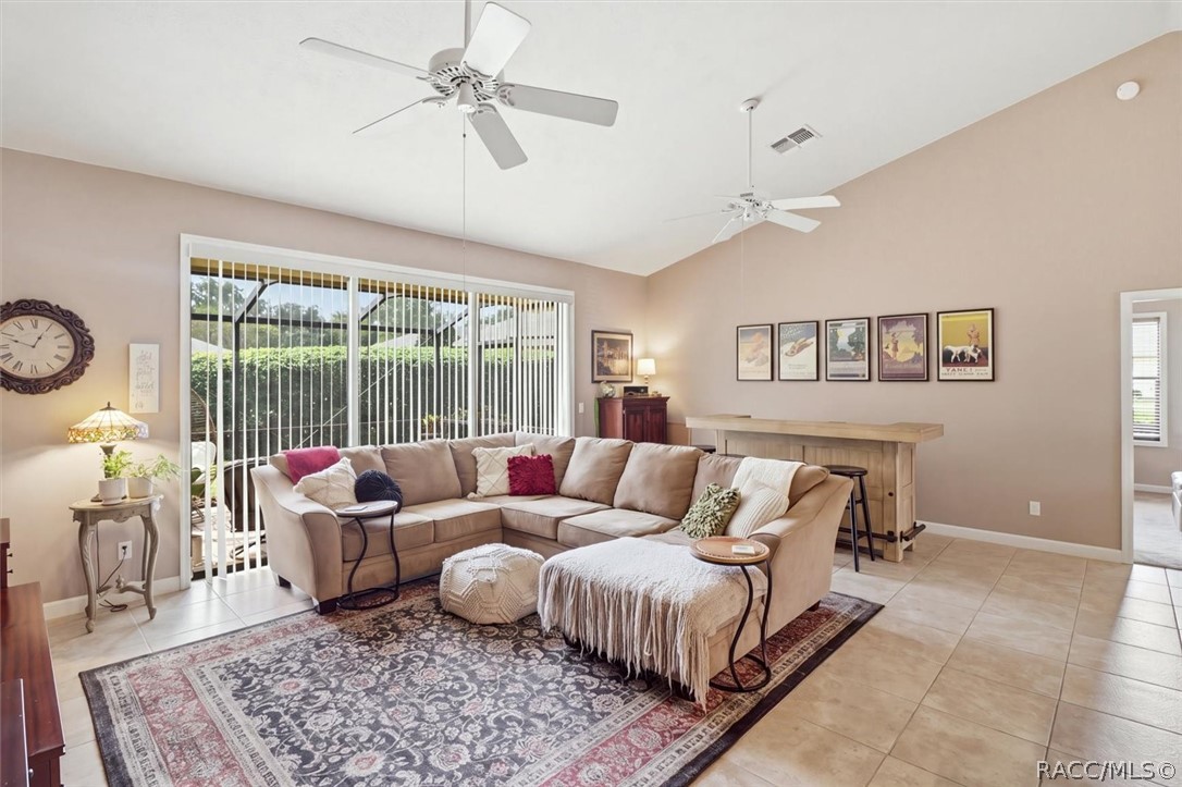 Staged living room with a beige sectional, patterned rug, and sliding glass doors overlooking greenery.