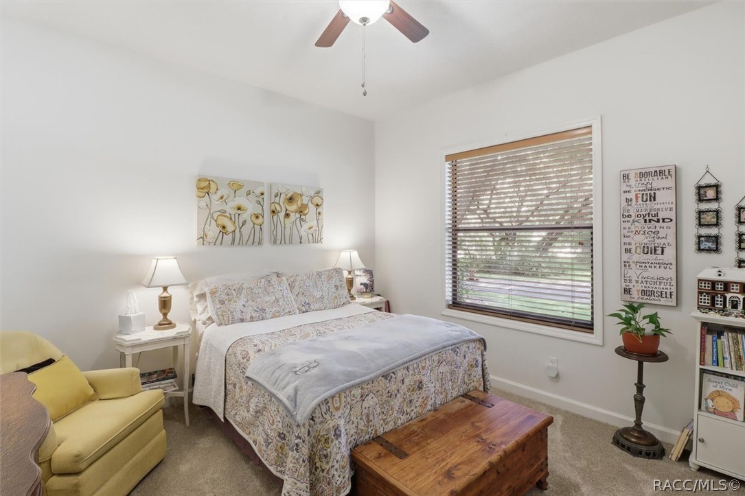 Bedroom with a patterned bed, yellow armchair, and wooden chest beneath the window.