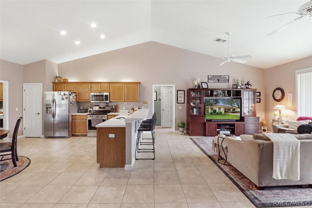 Open-plan kitchen and living room with a tiled floor, kitchen island, and furnished seating area.