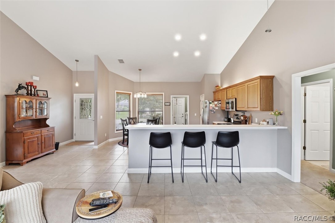 Open kitchen with a long breakfast bar, three black stools, and an adjoining dining area.