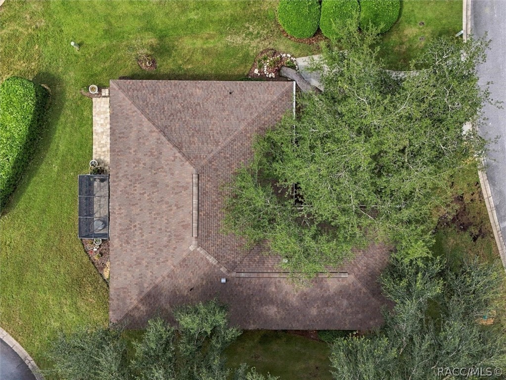 Overhead view of the home’s shingled roof, surrounded by lawn and mature trees.