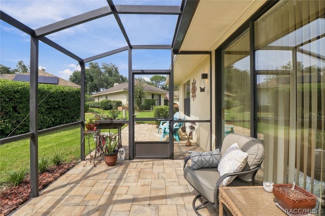 Screened patio with paver flooring, seating, and a view of the landscaped yard.
