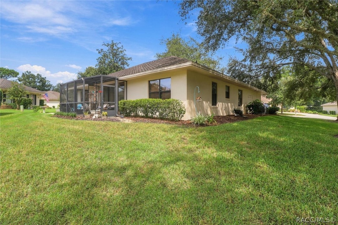 Single-story beige home with a screened patio, broad lawn, and mature trees.