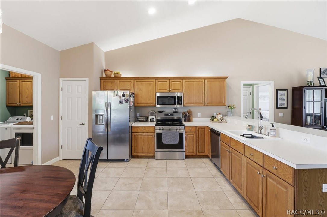 Kitchen with wood cabinets, stainless steel appliances, and a long white countertop.
