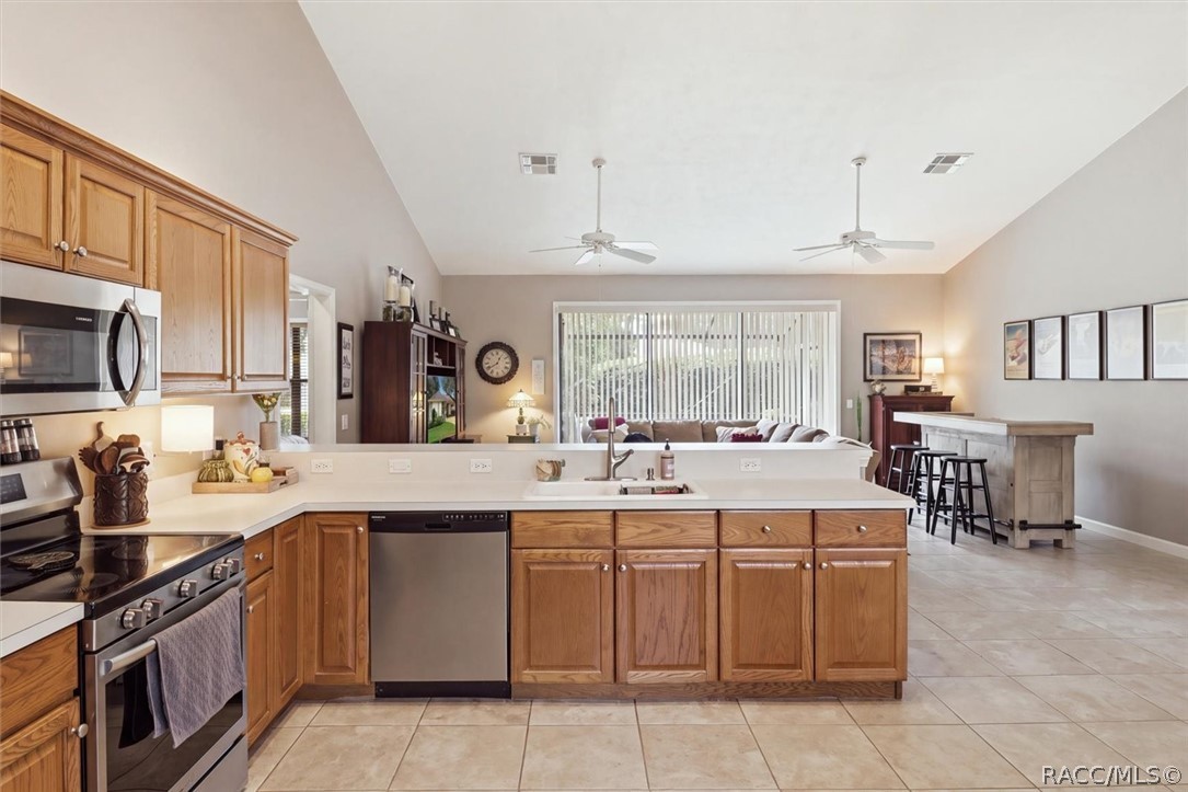 Open kitchen with warm wood cabinets, a central island, and adjoining living and dining areas.