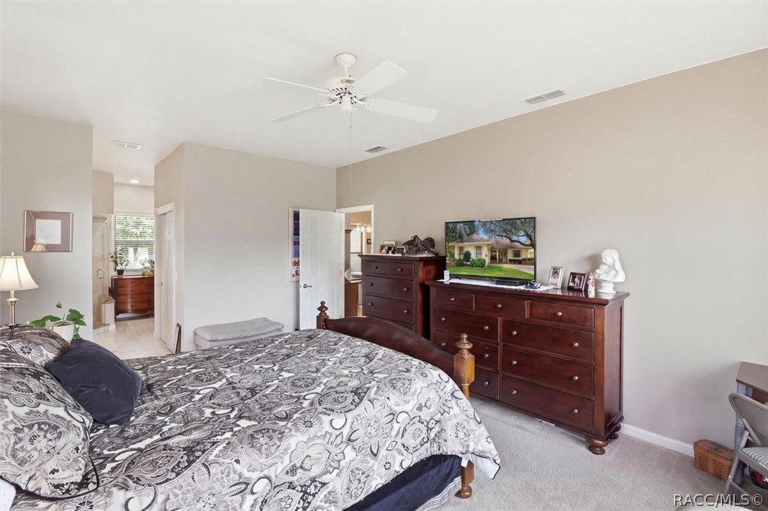Furnished bedroom with a patterned bedspread, dark wood dressers, and a ceiling fan.