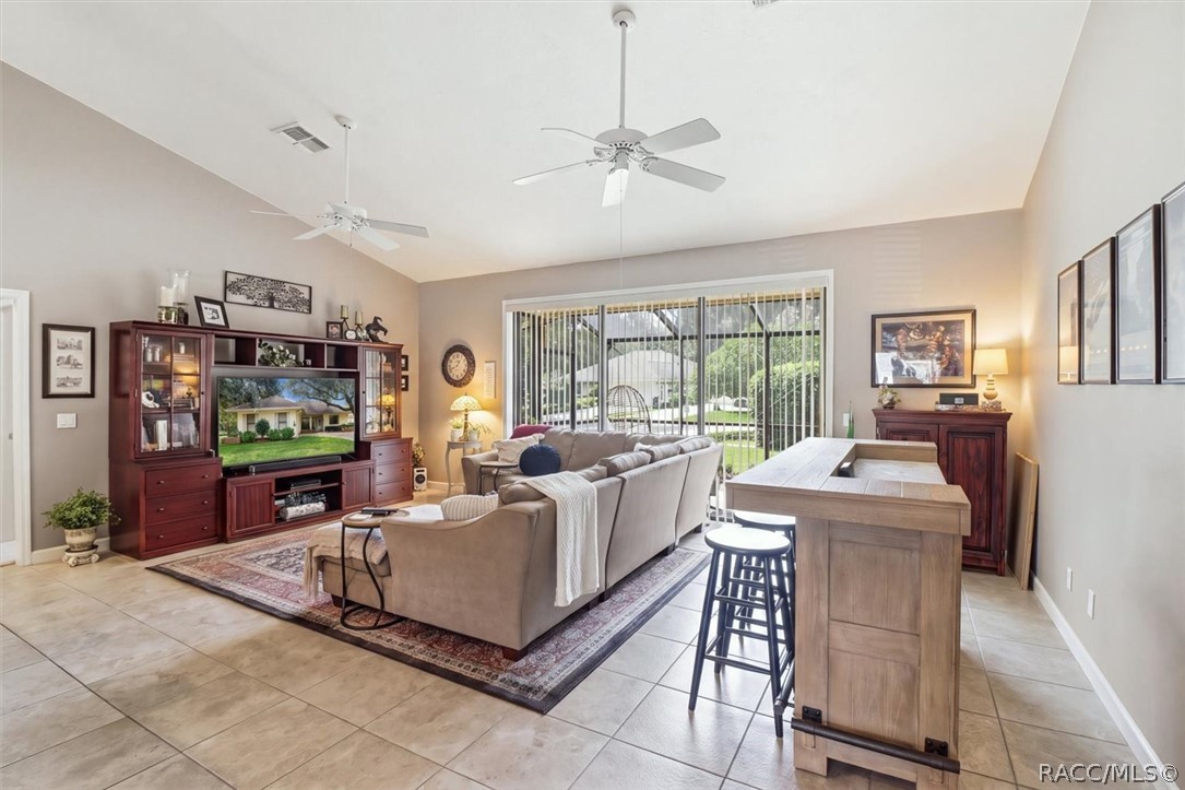 Furnished living room with a sectional sofa, entertainment center, and breakfast bar beside sliding glass doors.