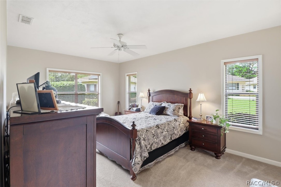 Bedroom with a dark wood bed, matching nightstand, and windows with white blinds.
