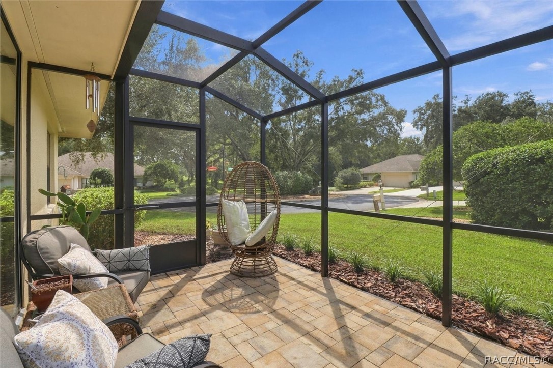 Screened patio with wicker egg chair and cushioned seating overlooking a green lawn.