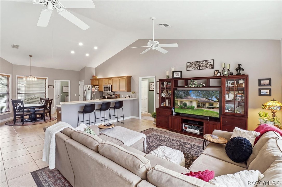 Open living room with a vaulted ceiling, sectional sofas, and an adjoining kitchen and dining area.