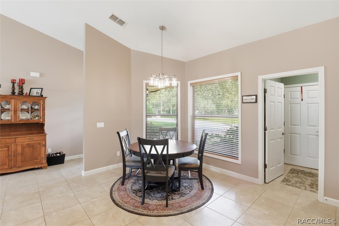 Dining room with a round table and chairs on a patterned rug beside large windows.