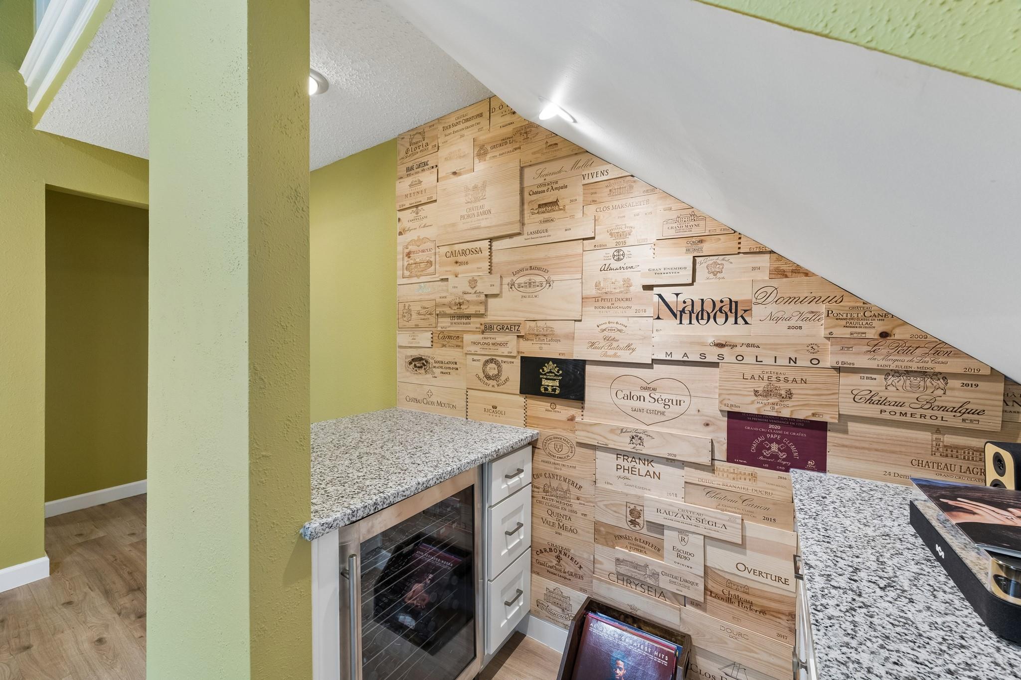 Wine bar with a wine-crate backsplash, granite counters, and an under-counter wine refrigerator.