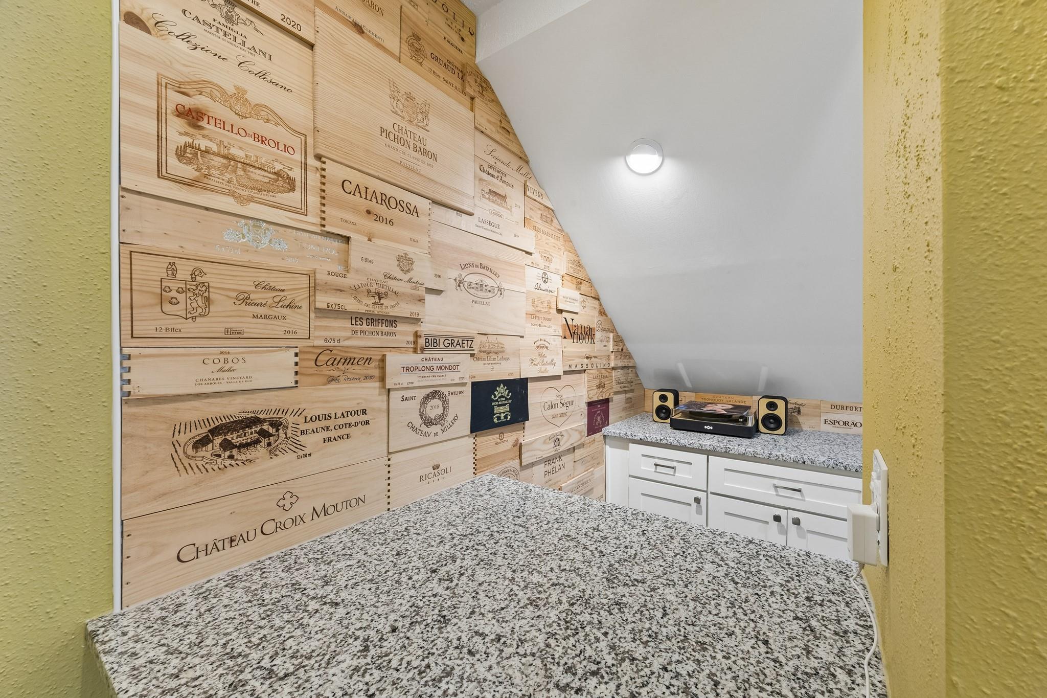 Wine cellar with engraved wooden wine crates, granite counters, and white cabinetry.