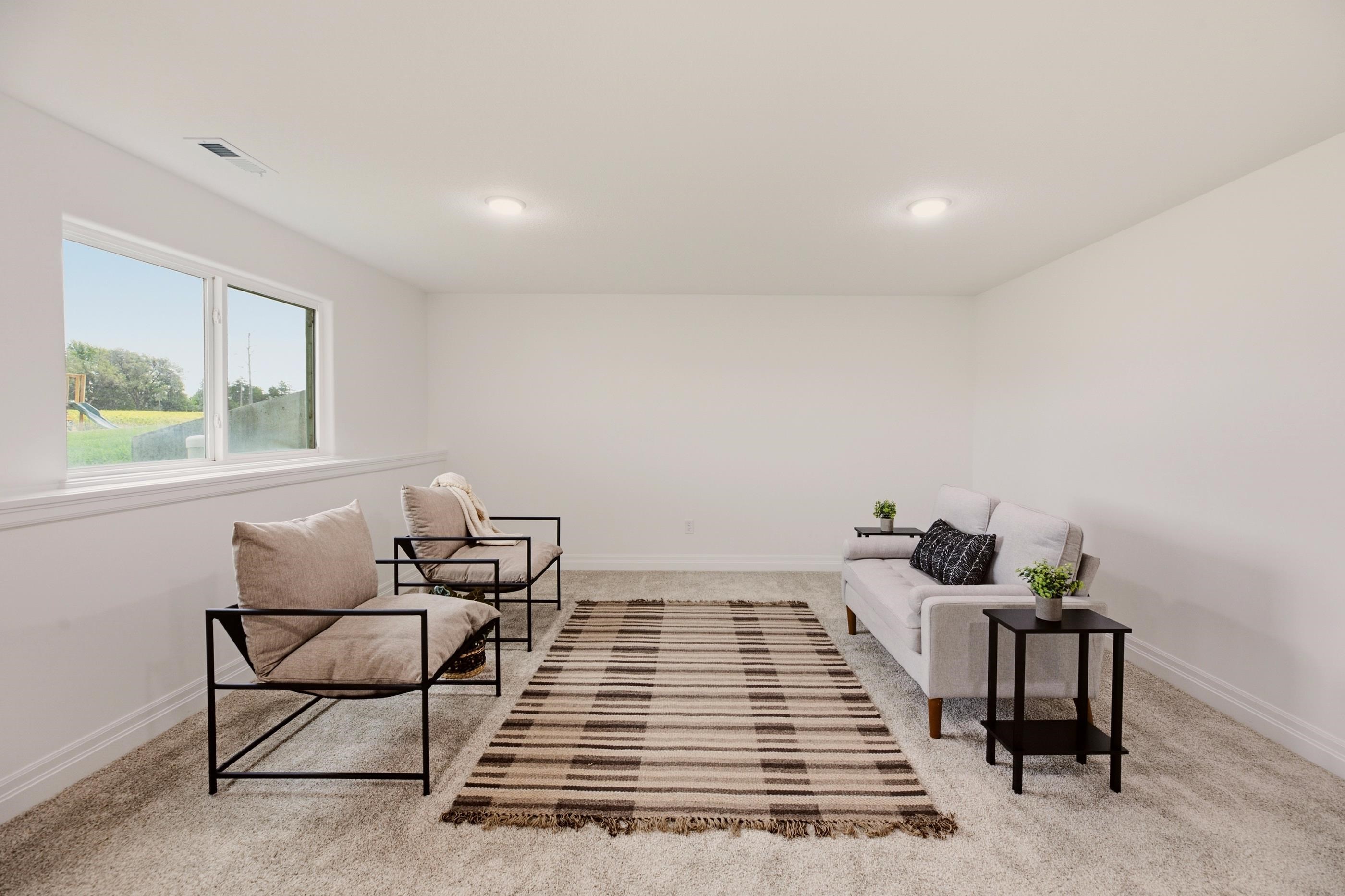 Staged living room with a light sofa, two armchairs, striped rug, and wide window.