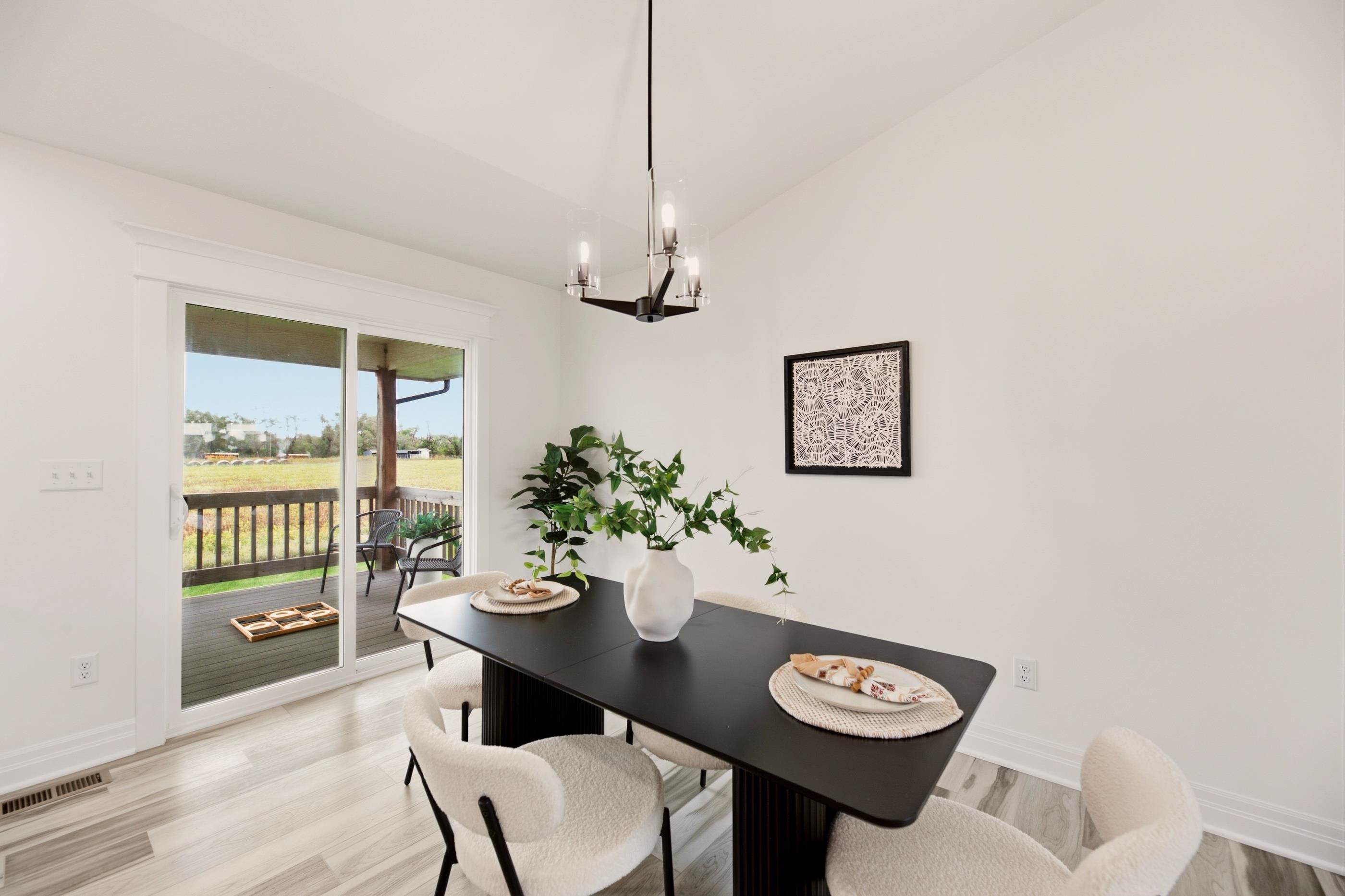 Dining room with a black table and cream chairs beside sliding doors to a covered deck.