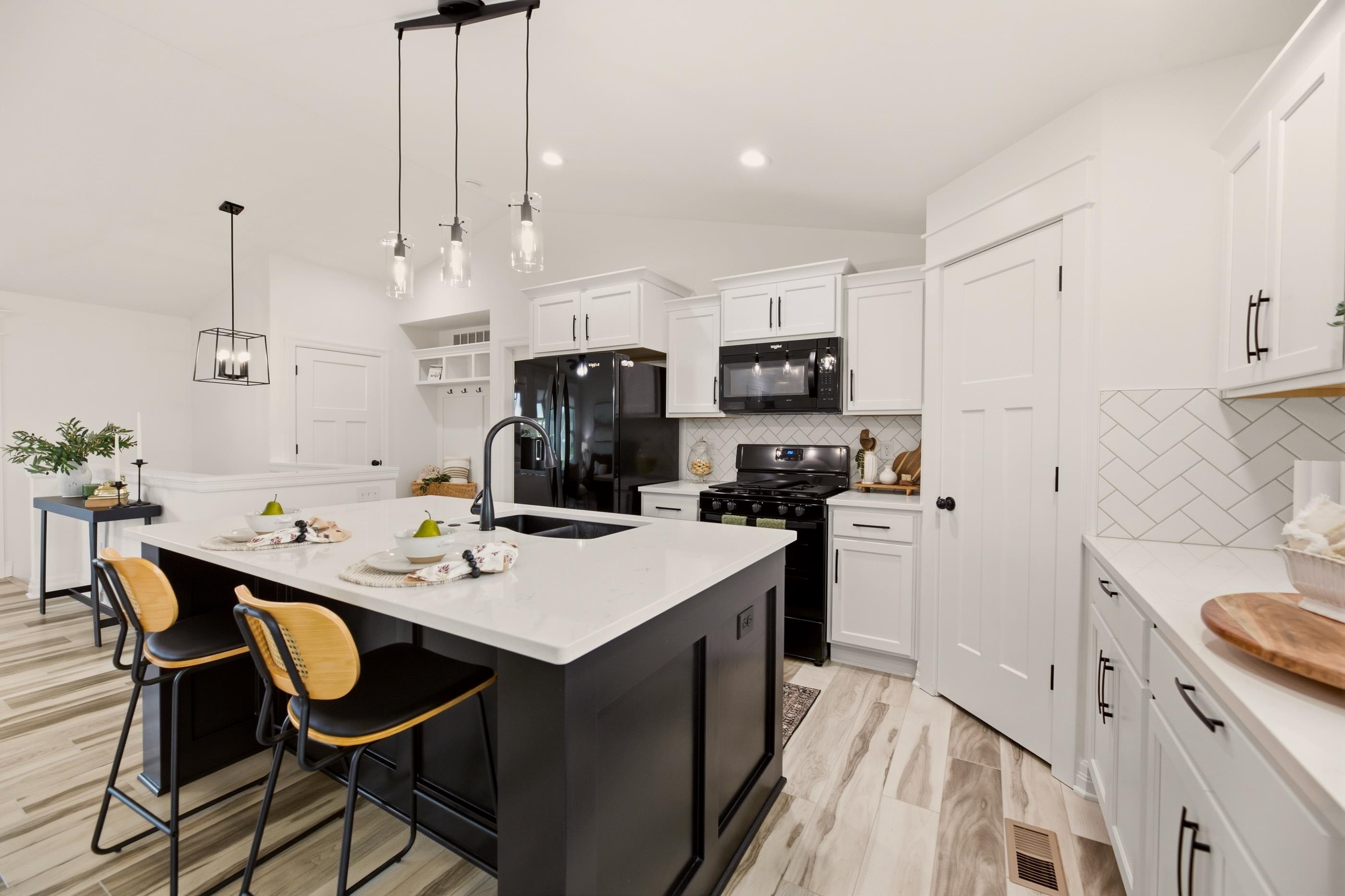 Staged kitchen with a large dark island, white cabinets, and black appliances.
