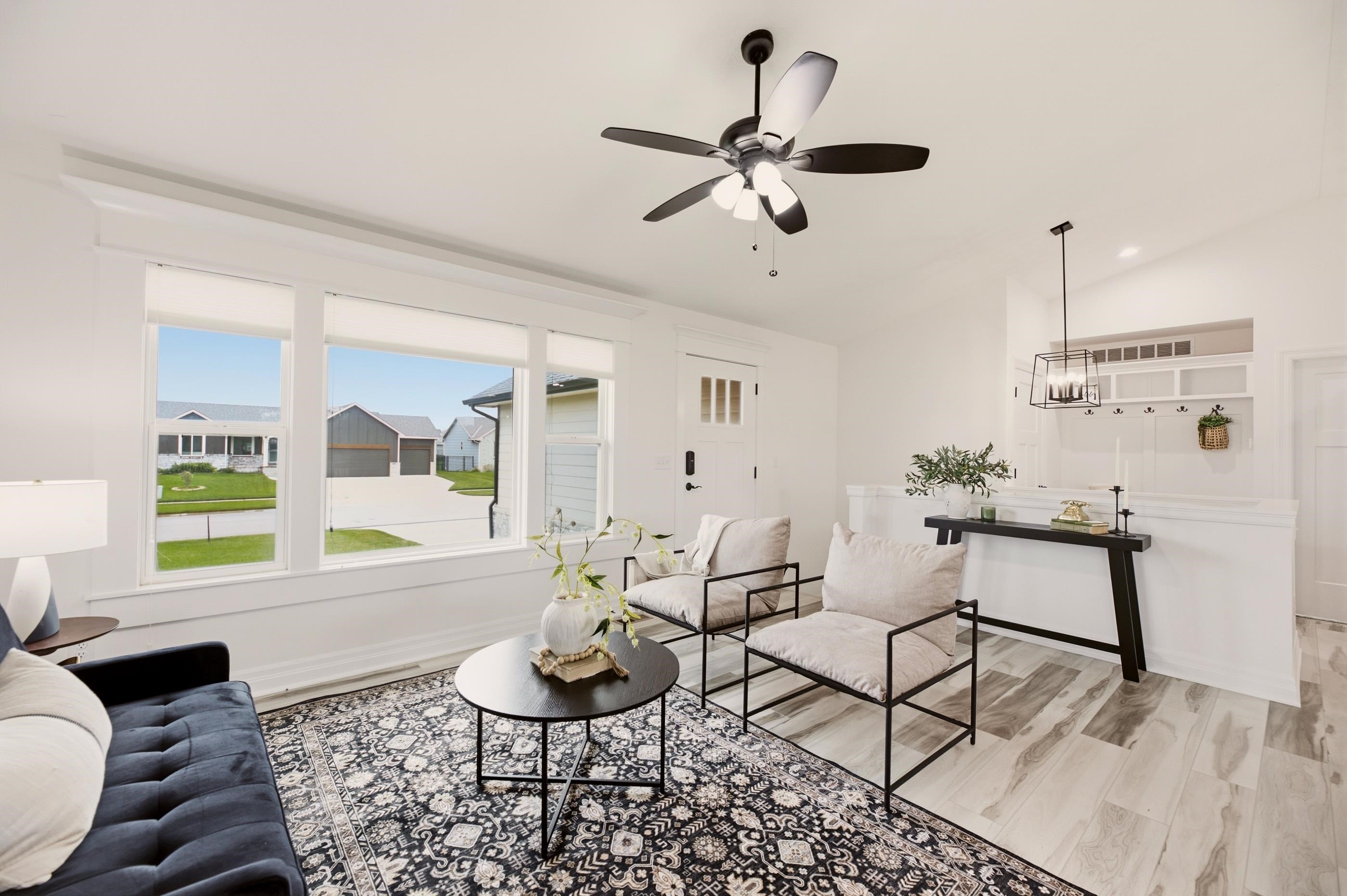 Staged living room with large windows, a patterned rug, and two armchairs.