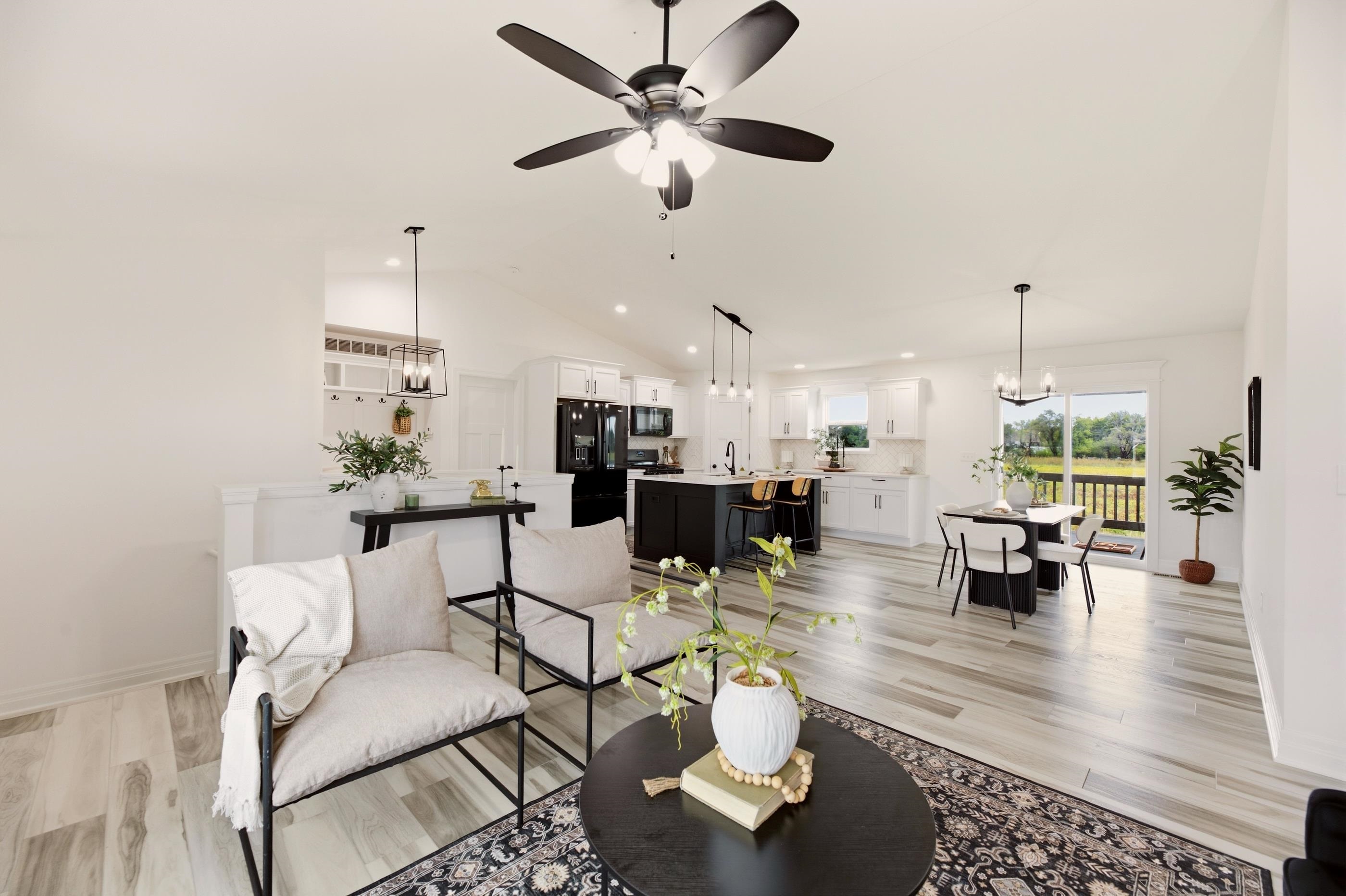 Open-plan living room and kitchen with a black island and sliding doors to a deck.
