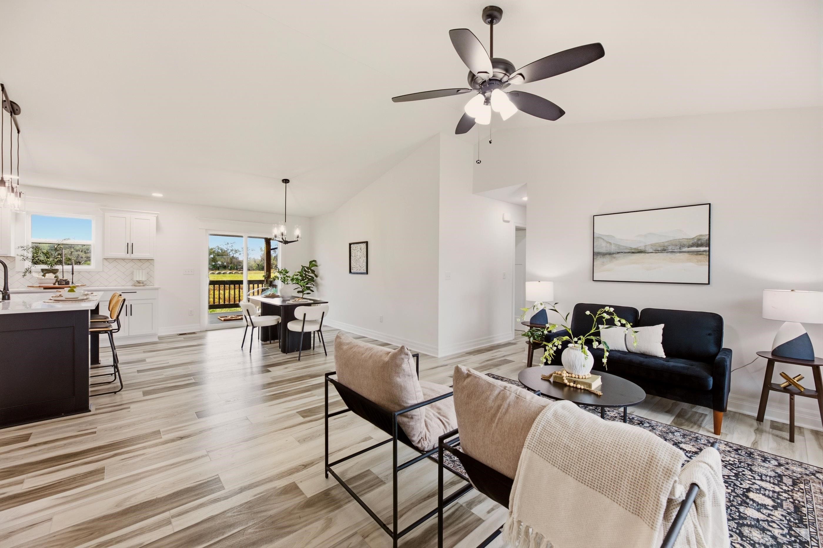 Open-plan living room and kitchen with white cabinets, a dining area, and sliding doors to a deck.