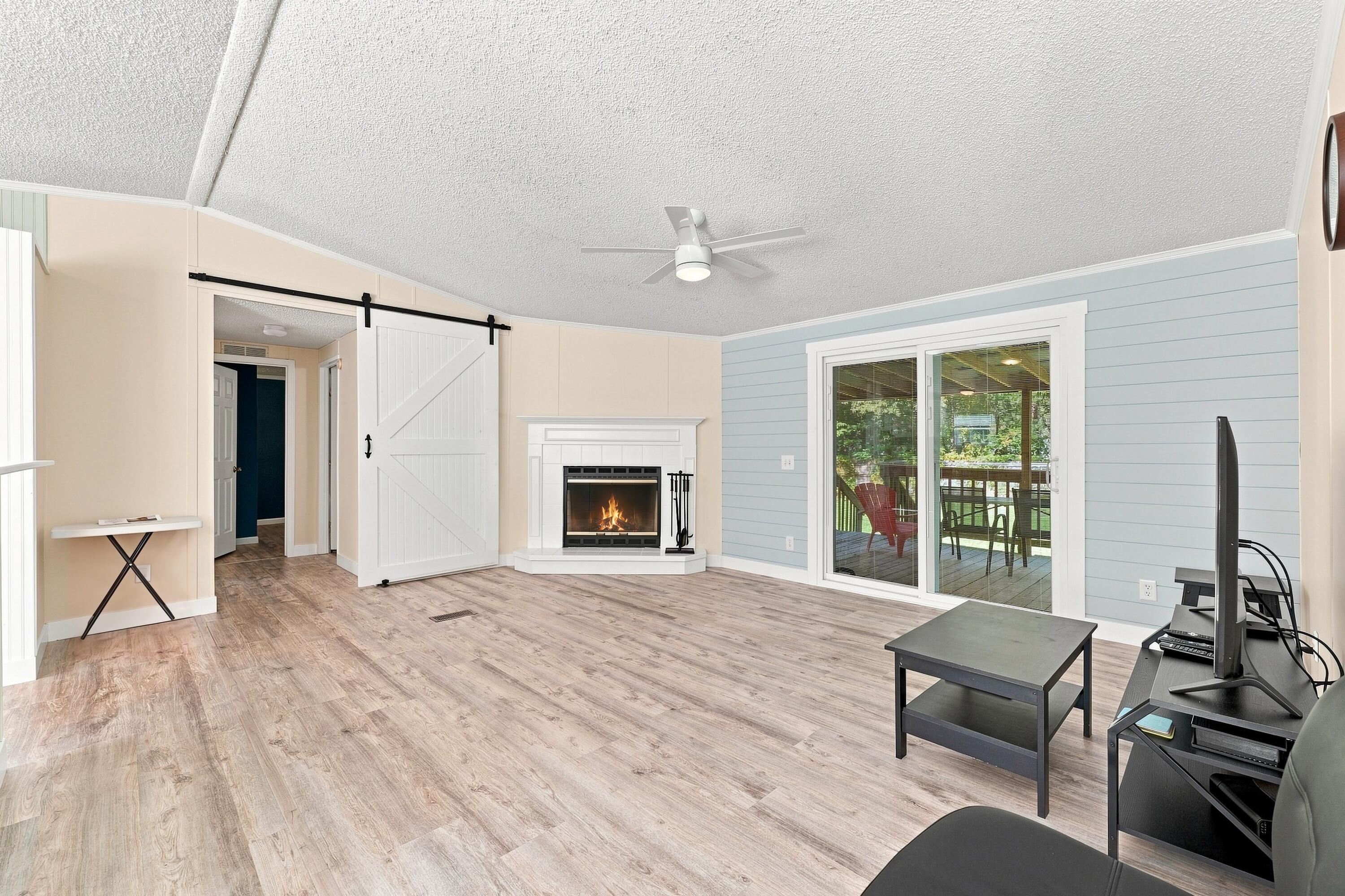 Living room with a white fireplace, sliding barn door, and glass doors to a covered deck.