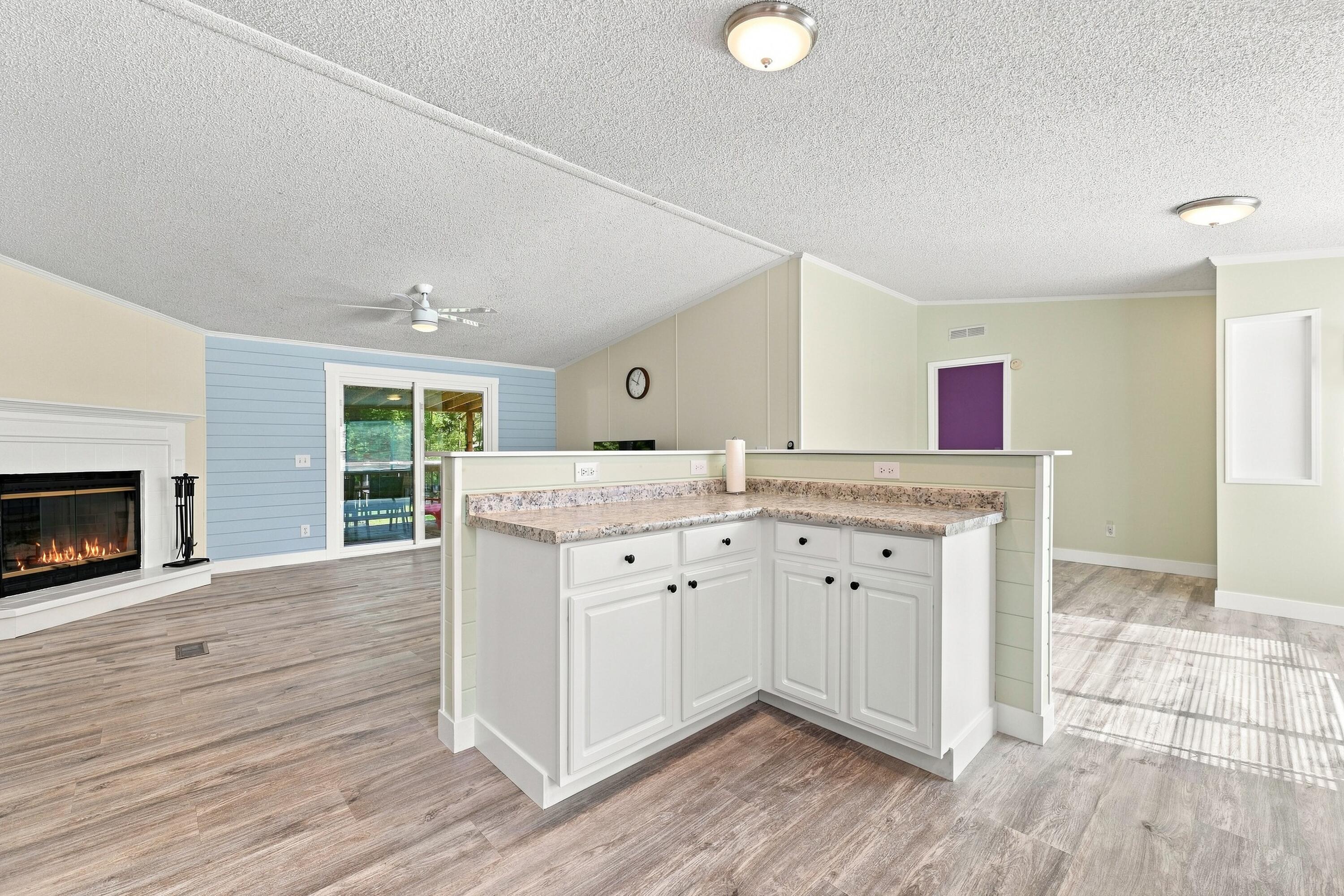 Open-plan living area with a granite-topped white breakfast bar, fireplace, and sliding glass doors.