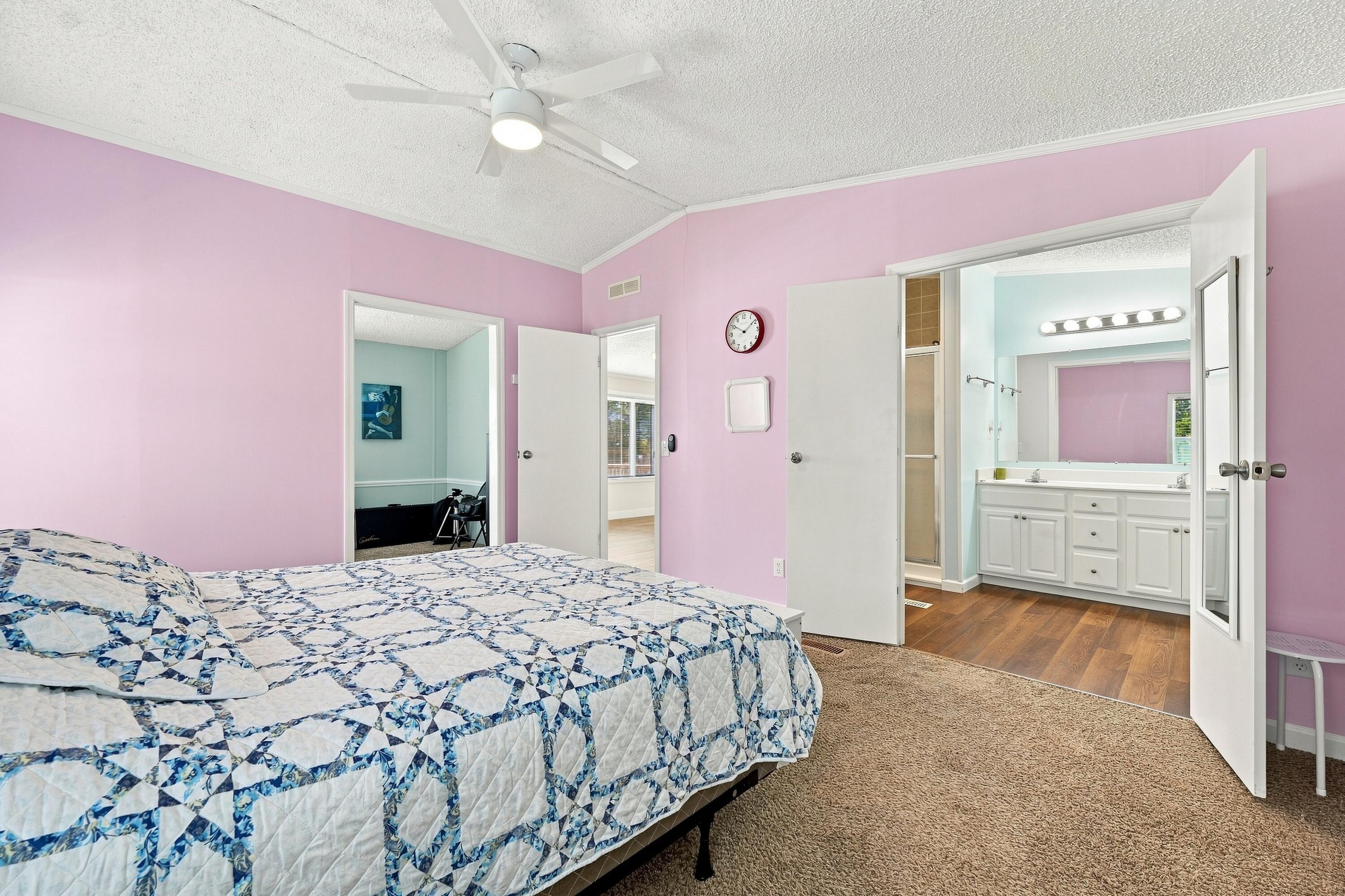 Bedroom with pink walls, a blue-and-white quilt, and an adjoining bathroom with a double vanity.