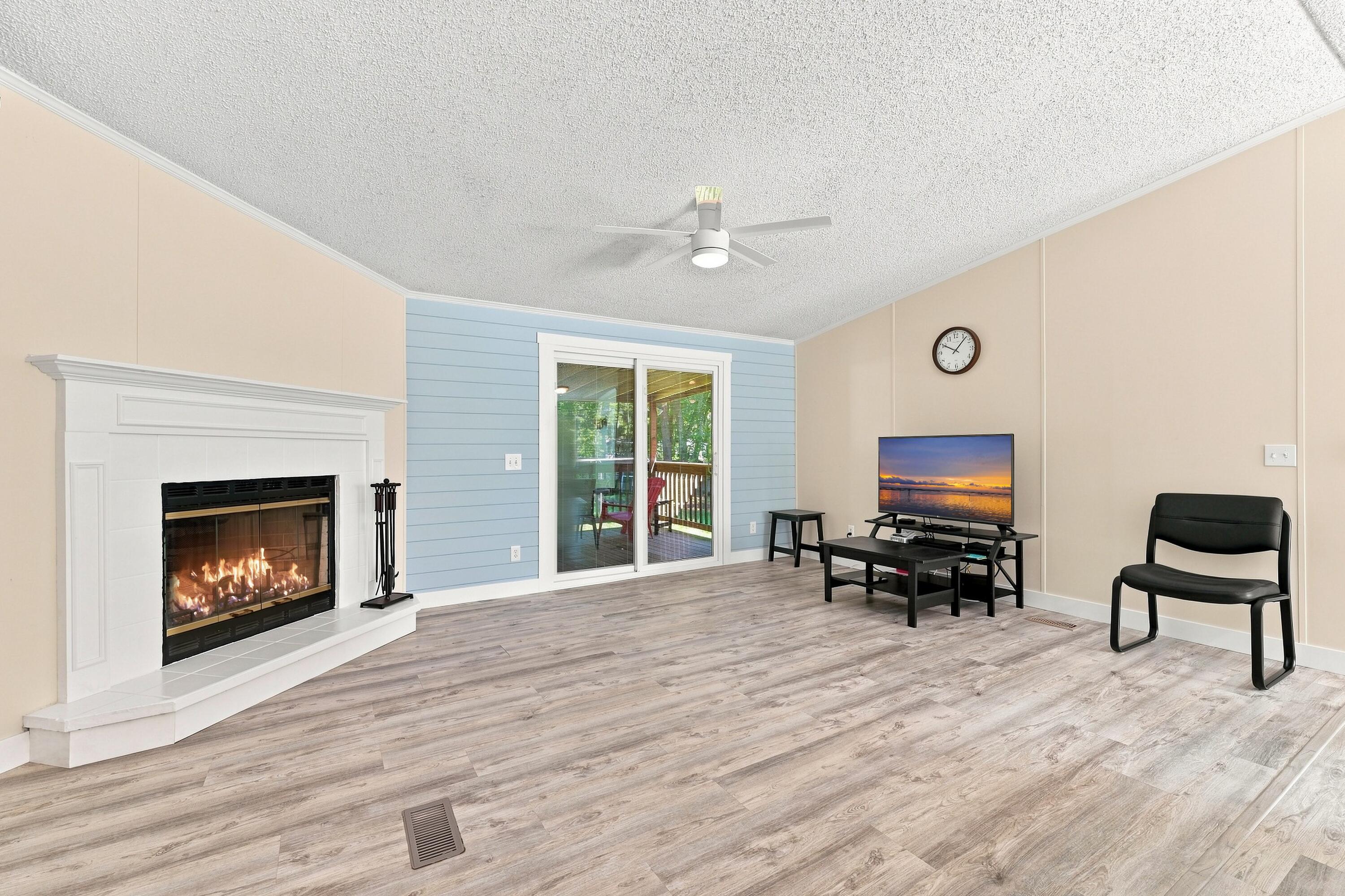 Living room with a lit fireplace, sliding glass doors to a deck, and a television.