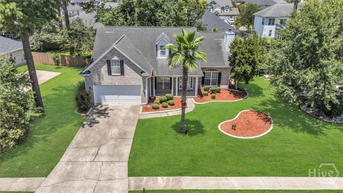 Aerial view of a gray-brick home with a palm tree, landscaped lawn, and two-car garage.
