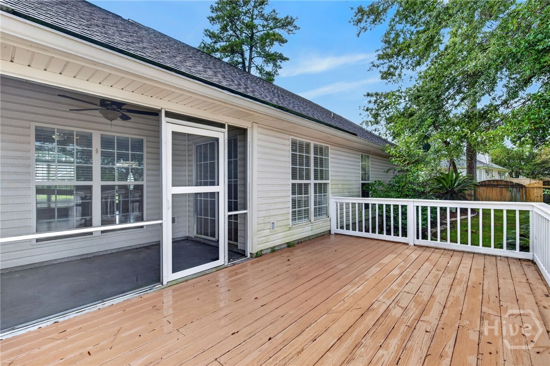 Rear deck with white railings beside a screened porch and leafy yard.