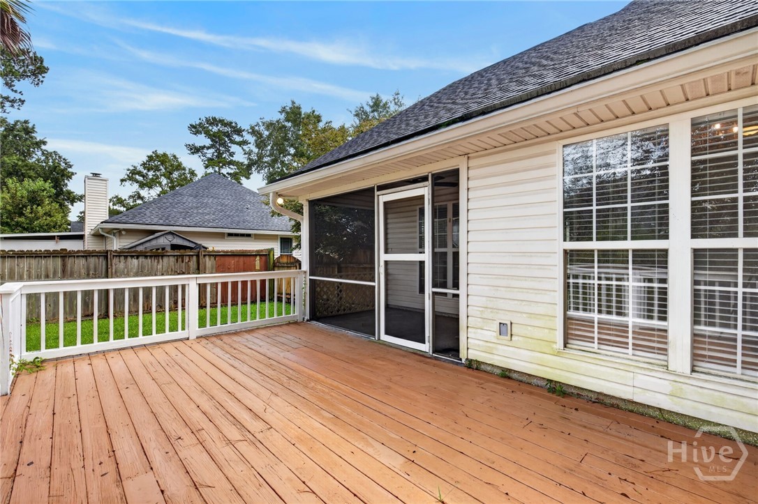Wooden deck beside the house, with white railings and a screened porch entrance.