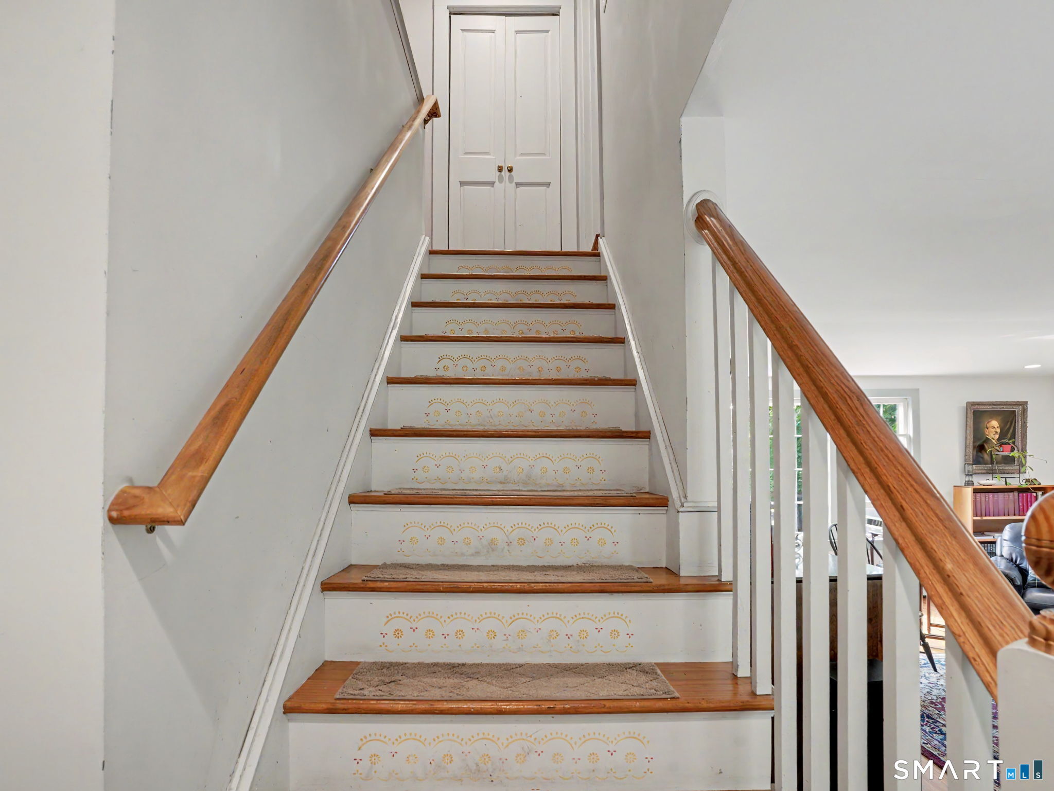 Interior staircase with gold-patterned risers, wood handrails, and double doors at the top.