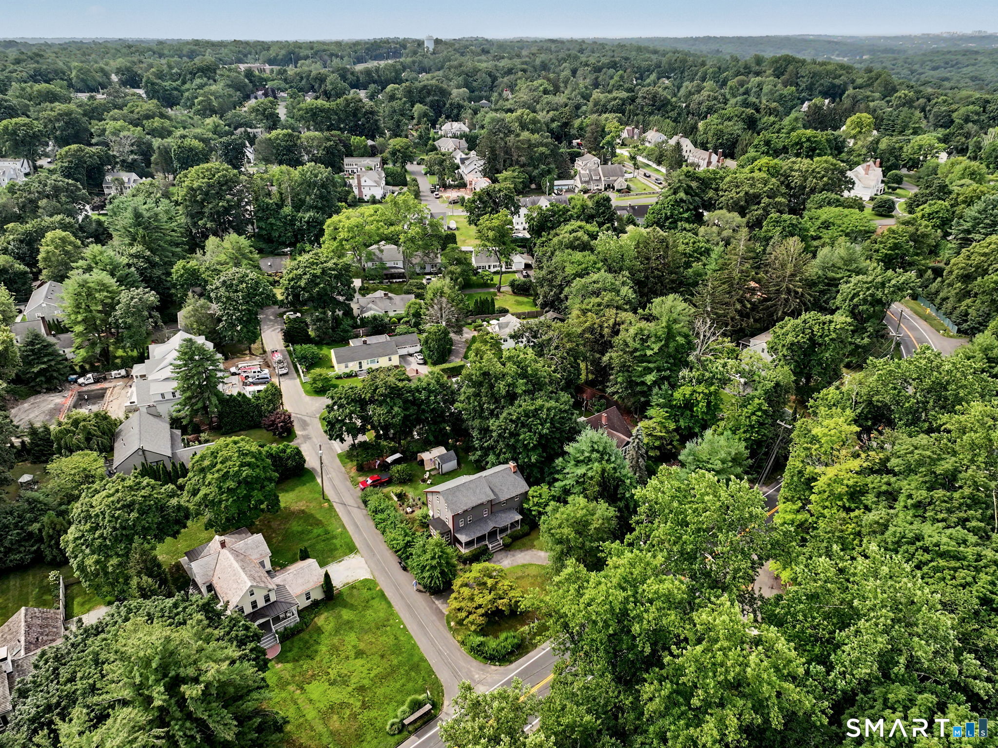 Aerial view of a leafy New Canaan neighborhood with homes and tree-lined streets.