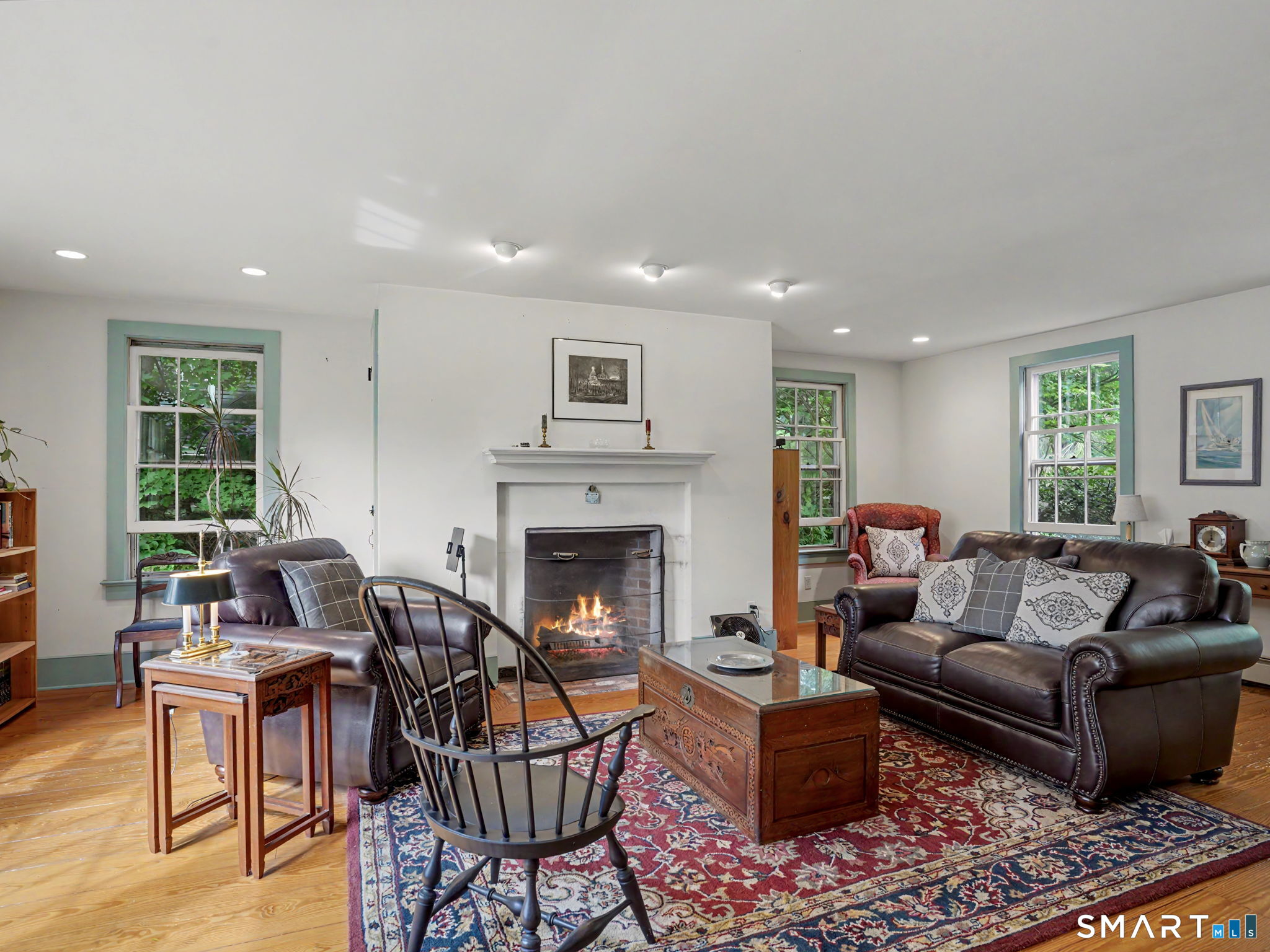 Living room with a lit fireplace, leather sofas, and a carved trunk coffee table.