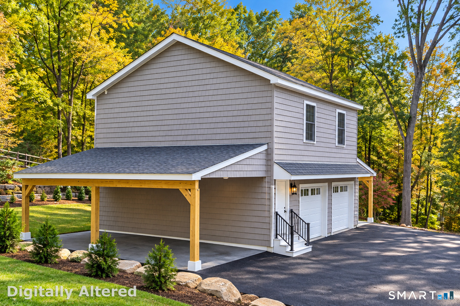 Gray two-story garage with a covered carport, paved driveway, and autumn trees.