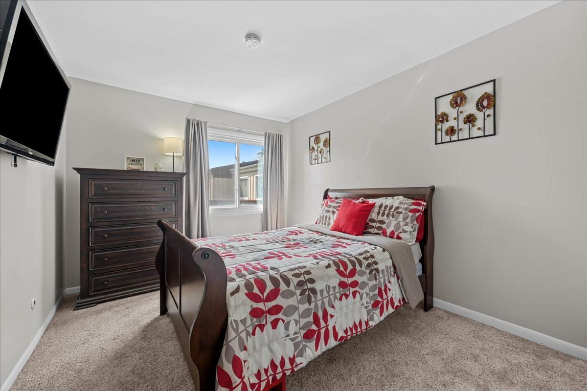 Bedroom with a dark wood sleigh bed, patterned red-and-gray bedding, and matching dresser.