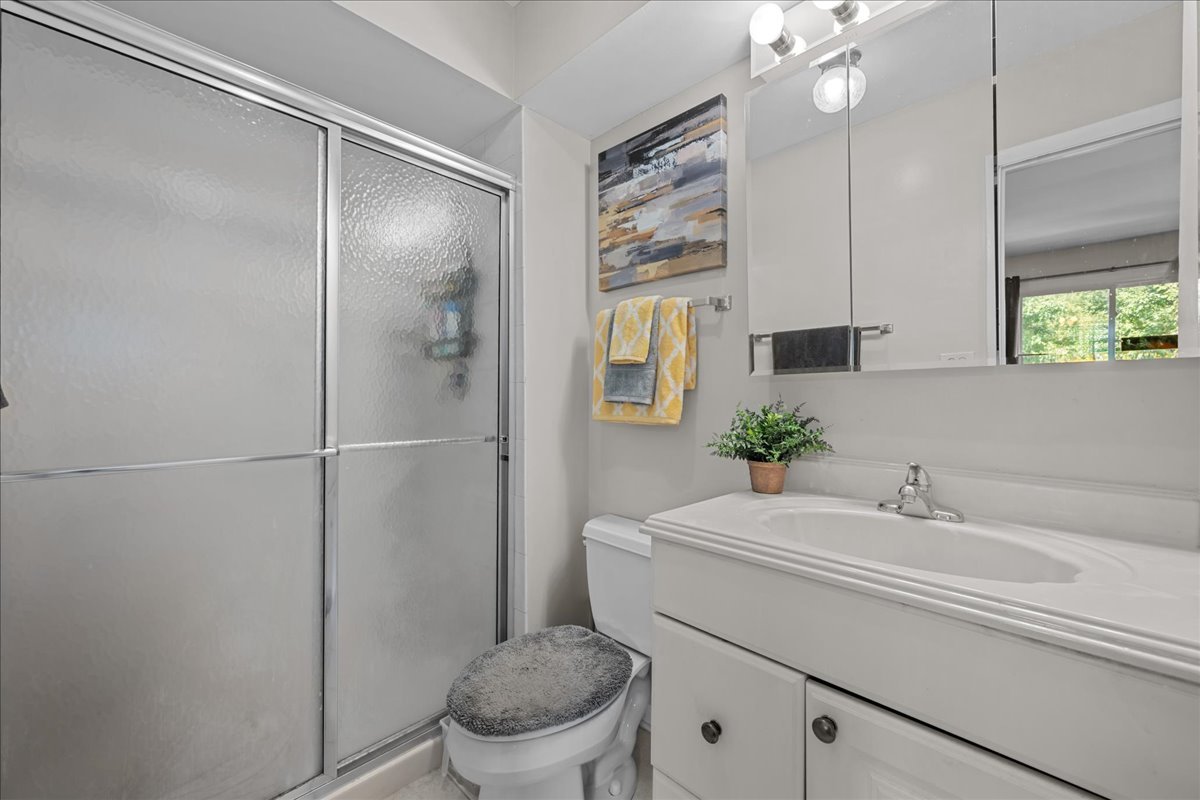 Bathroom with a frosted-glass shower, bathtub vanity, and yellow towels.