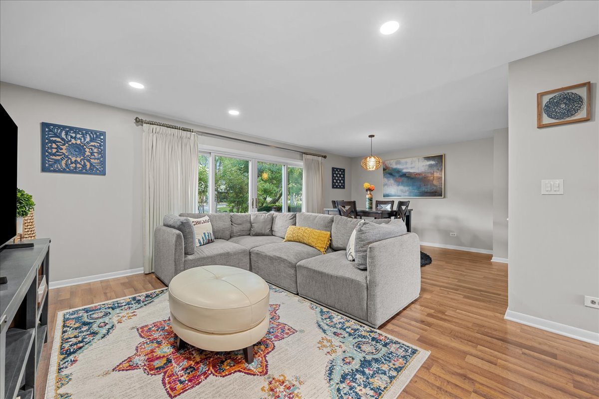 Living room with a gray sectional, colorful patterned rug, and adjoining dining area.