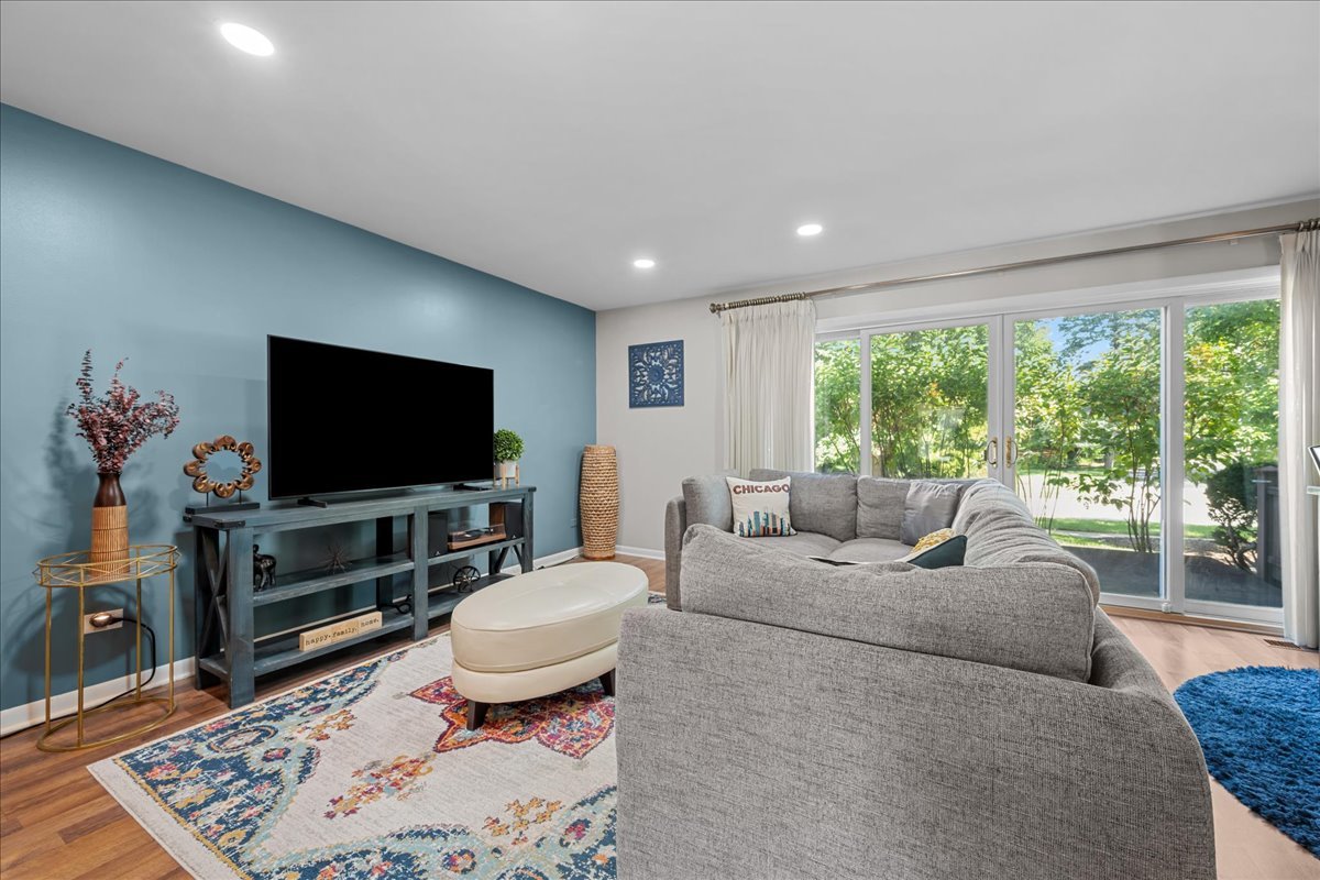 Living room with a gray sectional, blue accent wall, and sliding glass doors overlooking greenery.