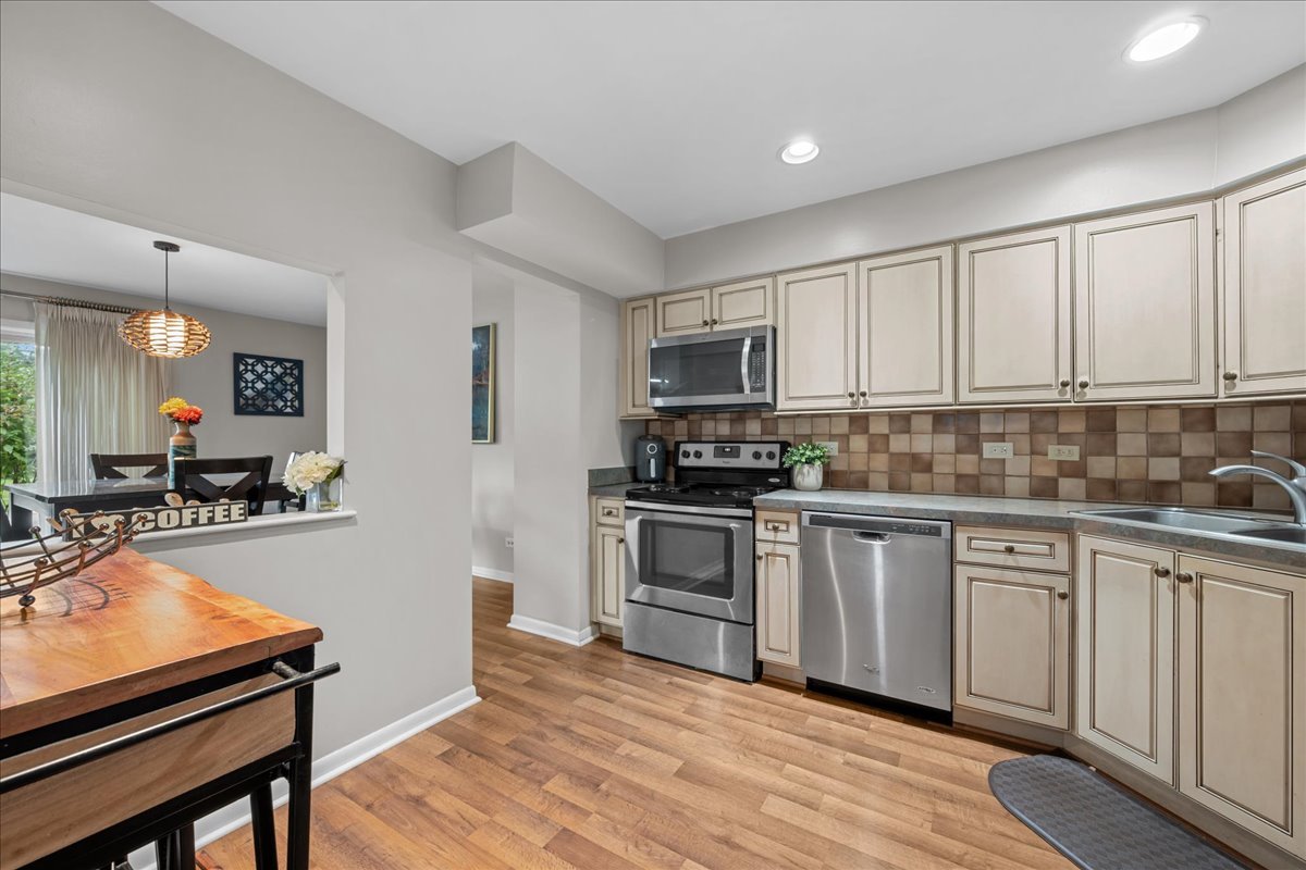 Kitchen with cream cabinetry, stainless steel appliances, and a dining area beyond the counter.