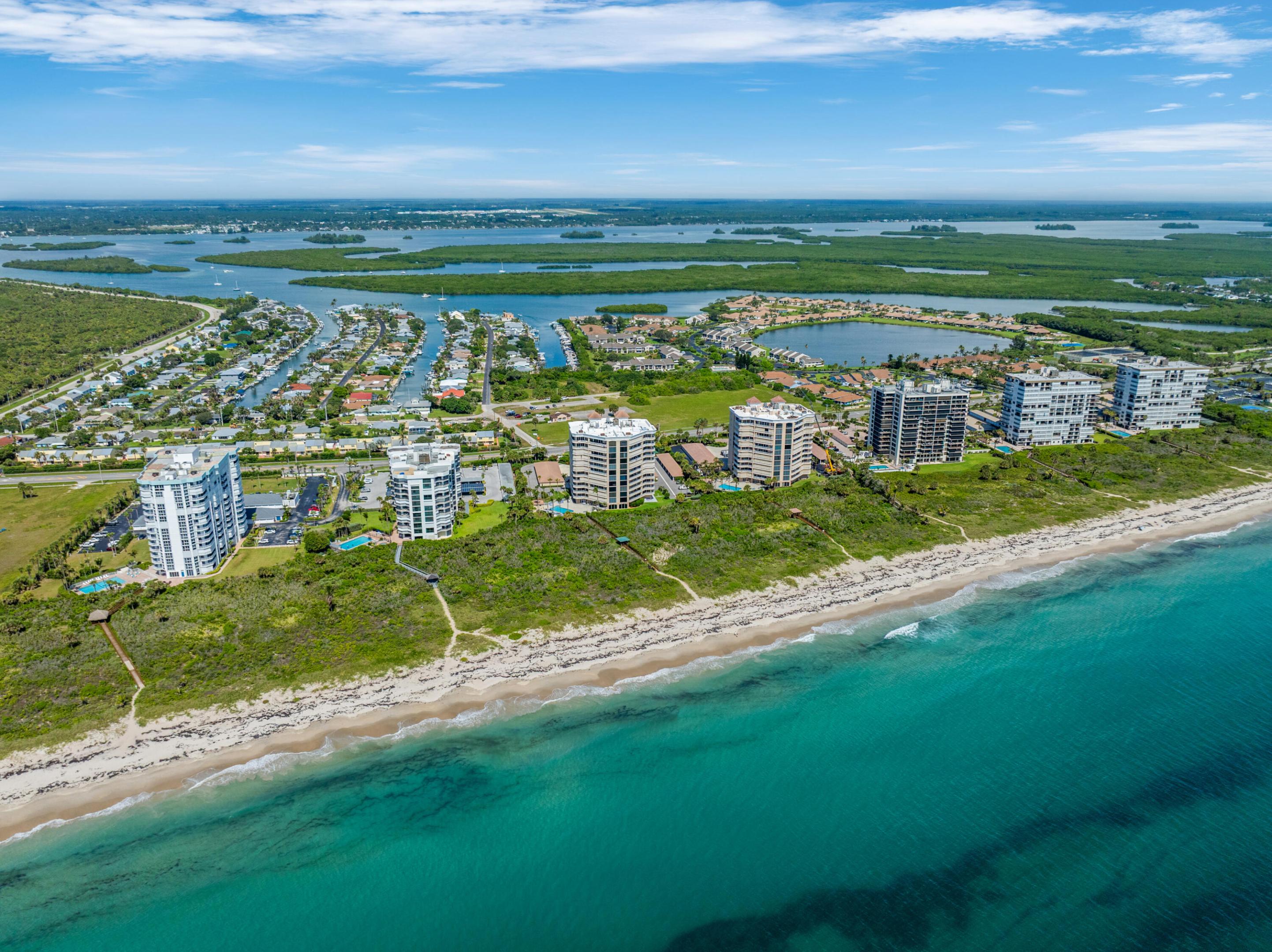 Aerial view of North Hutchinson Island condos along a sandy beach, with turquoise ocean and lagoon waterways.