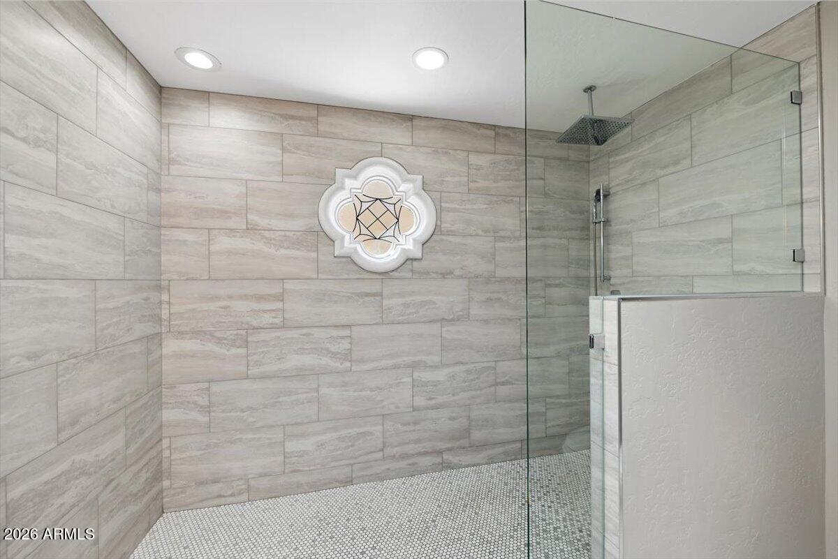 Walk-in shower with clear glass panels, a rainfall showerhead, and a decorative tile medallion.